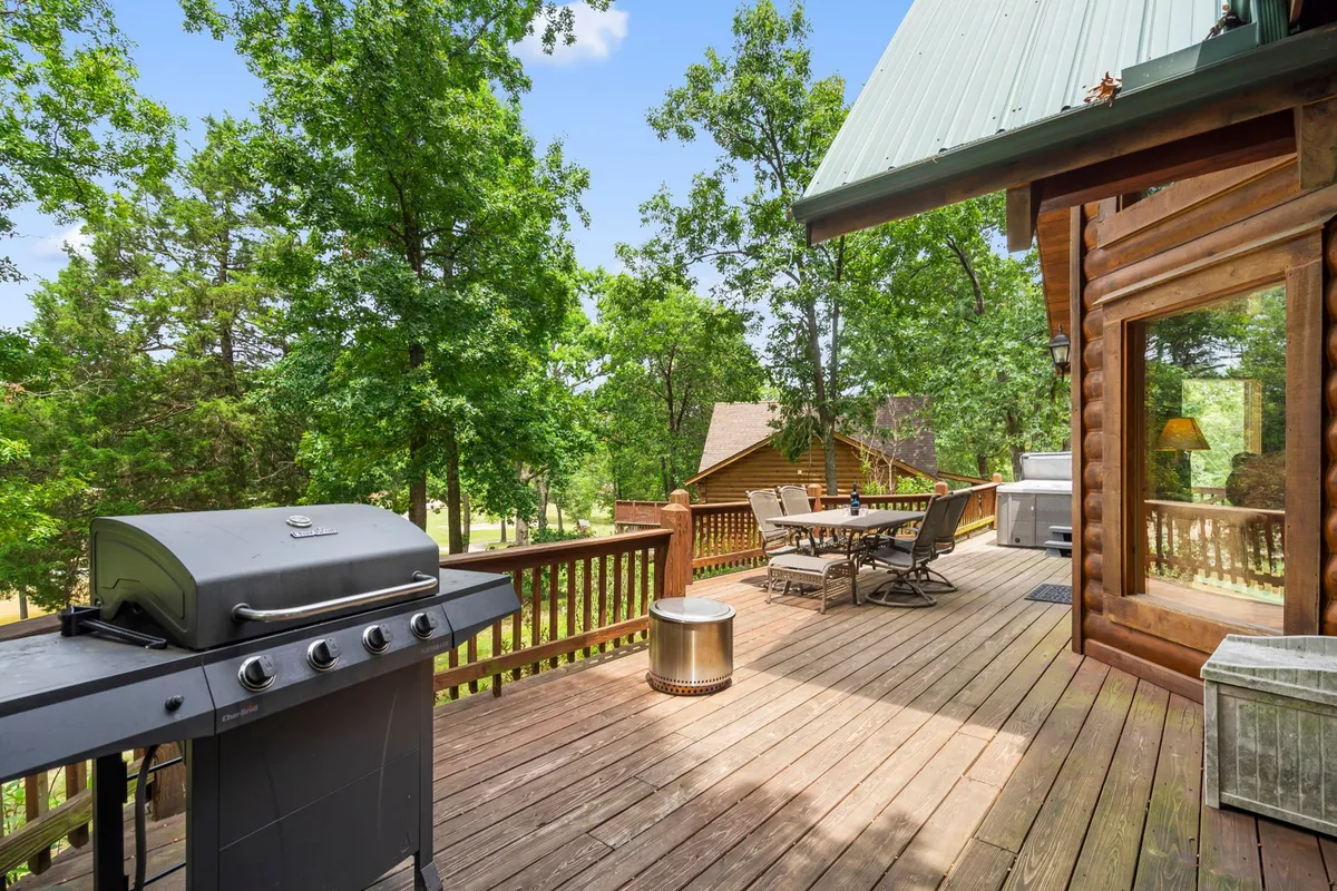 This image shows a wooden deck with a BBQ grill and an outdoor dining table set against a backdrop of lush greenery. The setup is casual and inviting, signaling opportunities for group meals, sunset dinners, and enjoying nature together.